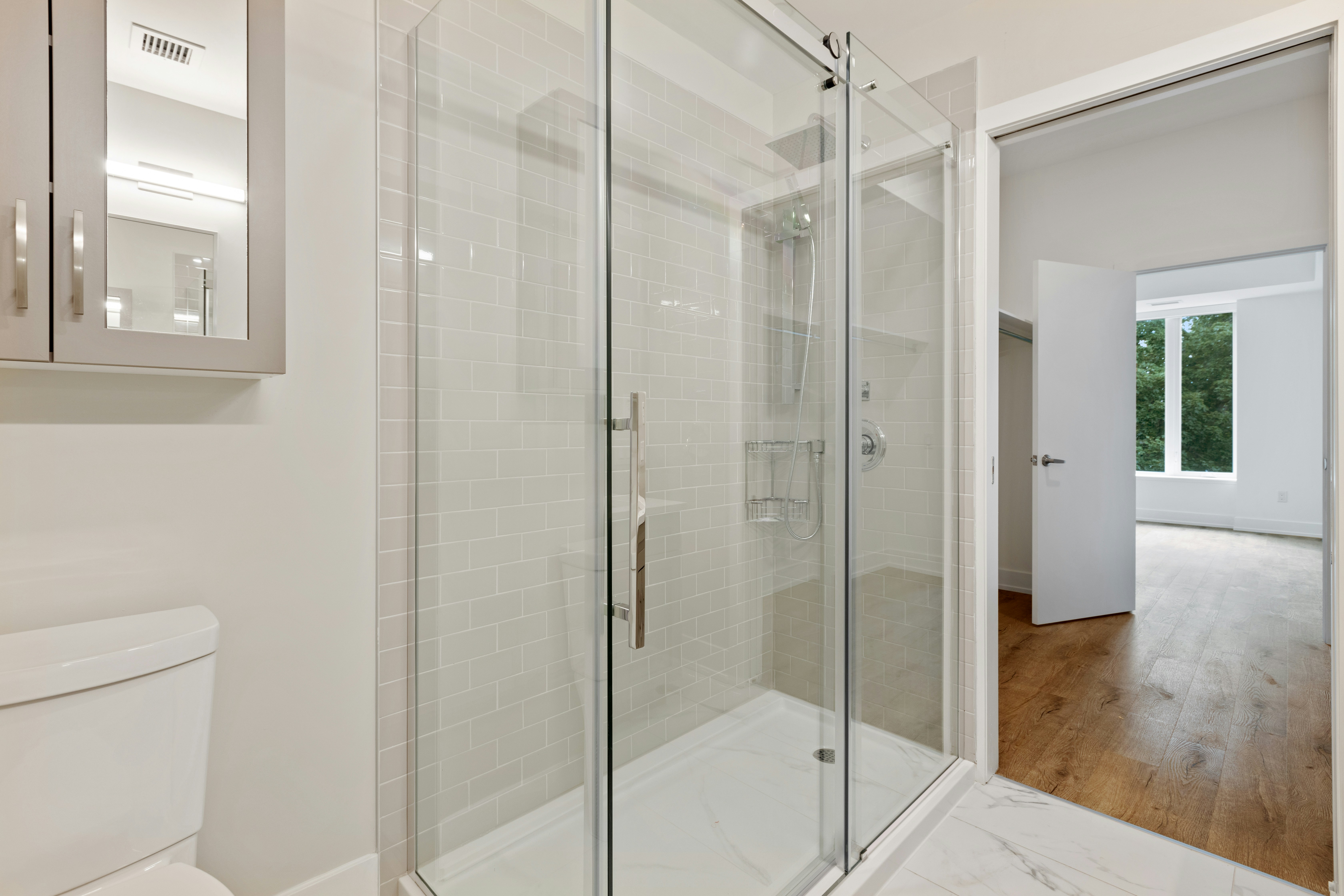 A frameless glass shower enclosure in a marble bathroom